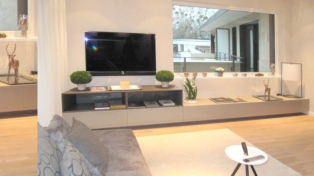 Niedriges Sideboard unter einem Fernseher vor einer Fensterfront